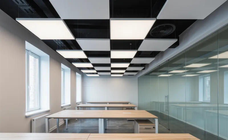 Oficina diáfana con placas acústicas decorativas suspendidas del techo sobre las mesas de trabajo